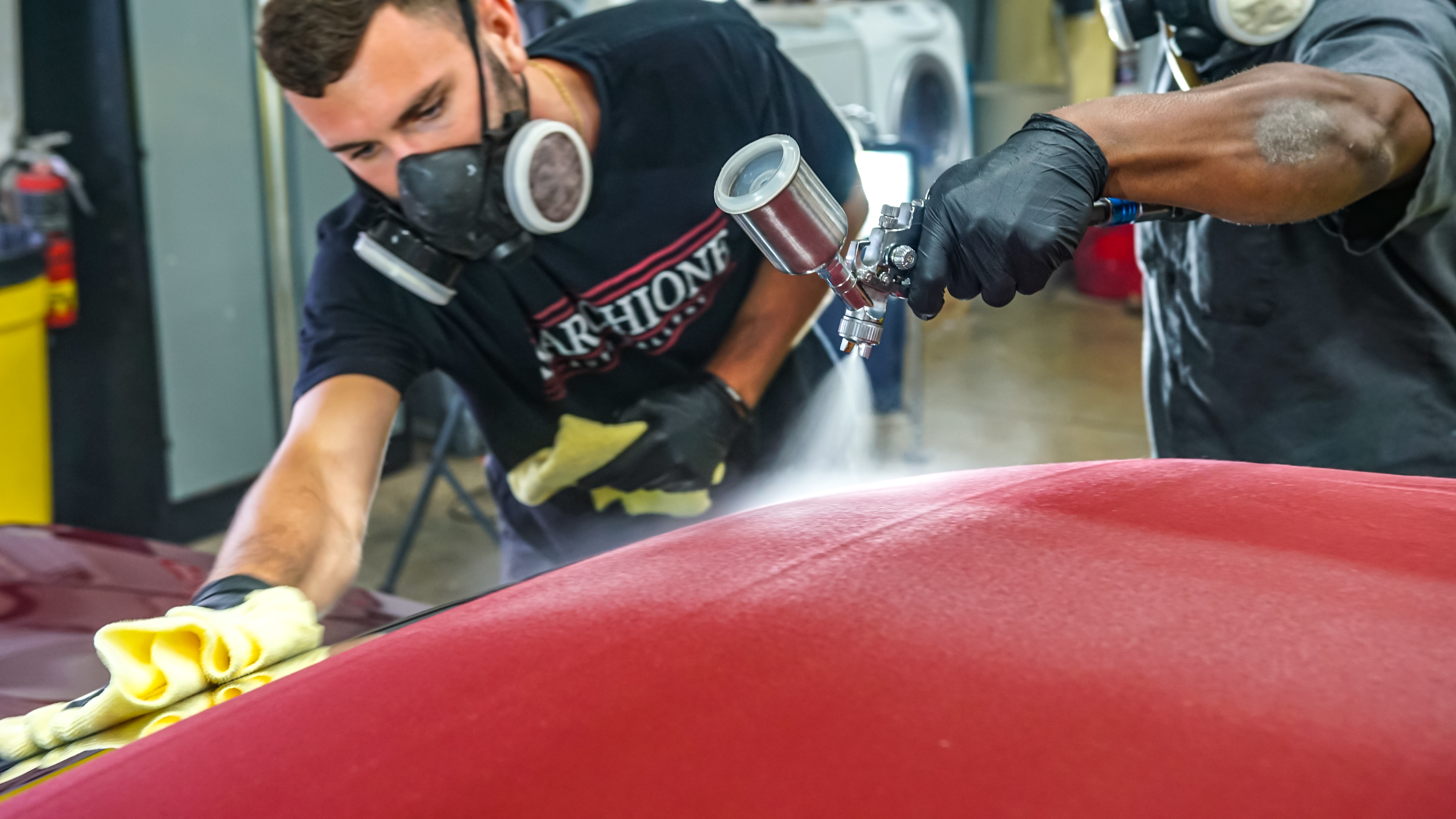 Team member applying ceramic coating with professional spray equipment